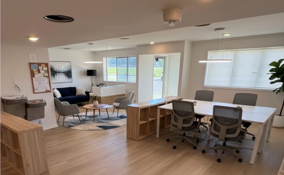 Modern office space with a lounge area, workstations, and natural light.