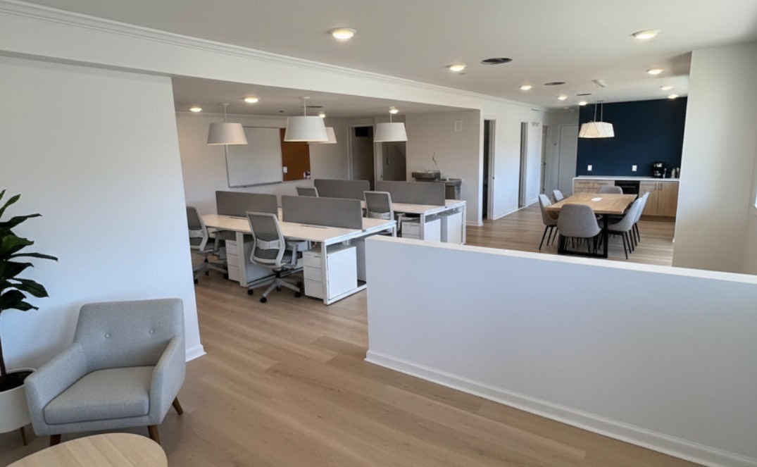 Modern open-plan office with shared workstations and a meeting area.